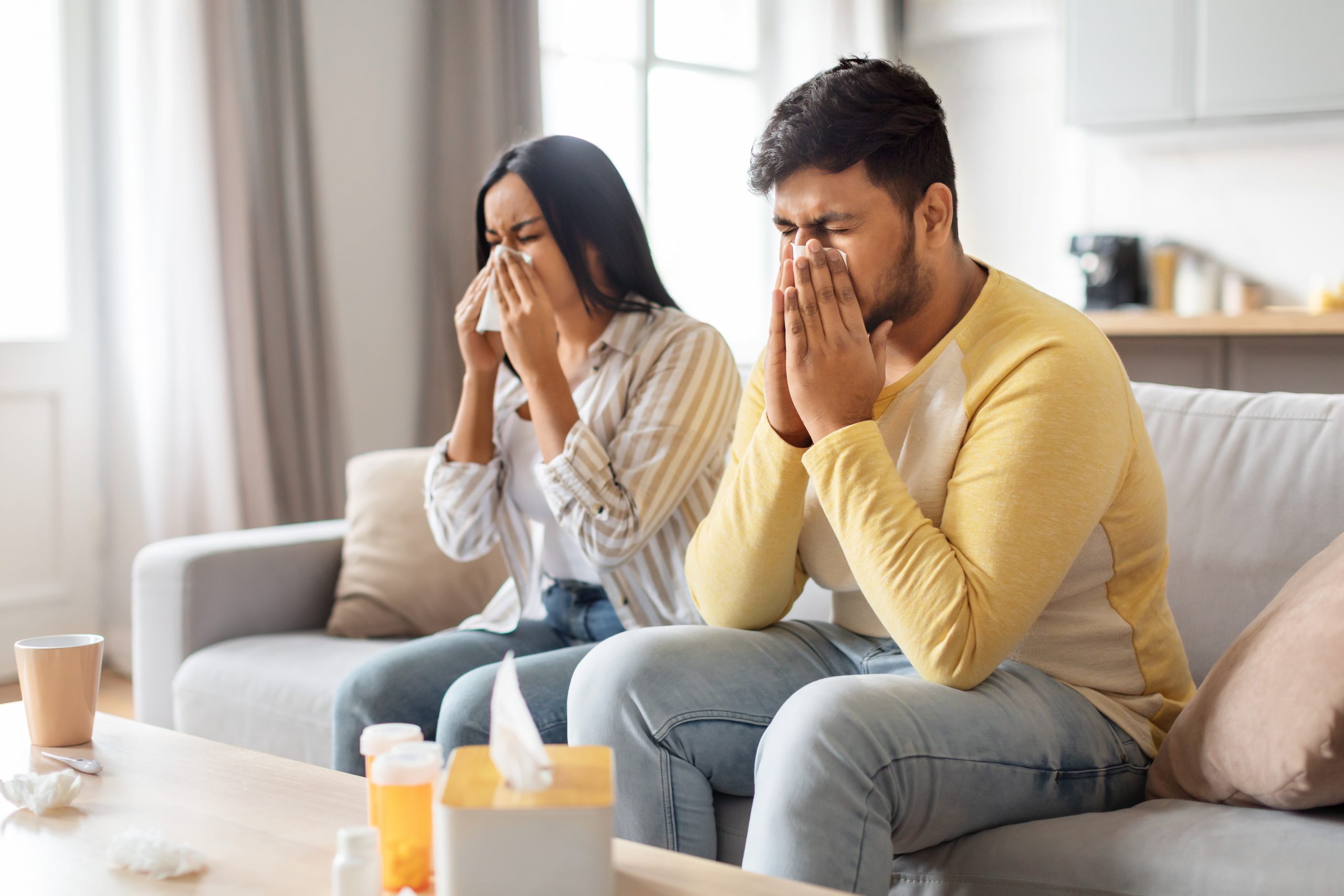 Pareja con síntomas de alergia a los ácaros, usando pañuelos para la congestión nasal