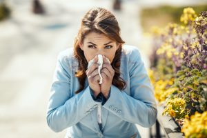 Mujer con síntomas de alergia estacional cerca de flores